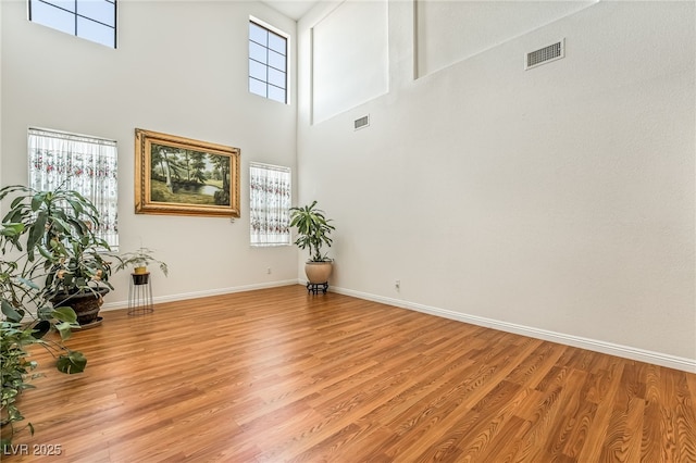 interior space with a towering ceiling, a wealth of natural light, and light wood-type flooring