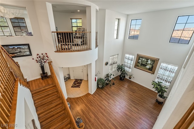 foyer entrance with hardwood / wood-style flooring, a wealth of natural light, and a towering ceiling