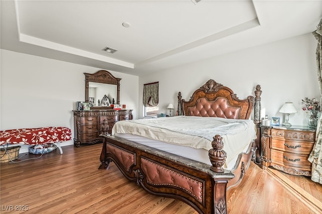 bedroom with a raised ceiling and hardwood / wood-style floors