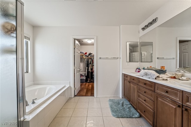 bathroom featuring vanity, tiled tub, and tile patterned flooring