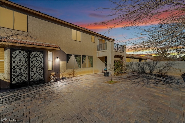 back house at dusk with a patio and a balcony