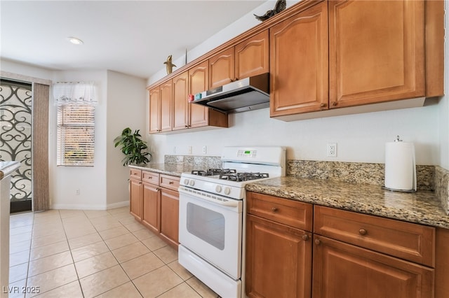 kitchen with light stone countertops, white gas stove, and light tile patterned floors