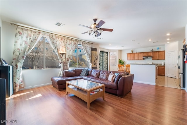 living room featuring ceiling fan and light hardwood / wood-style floors