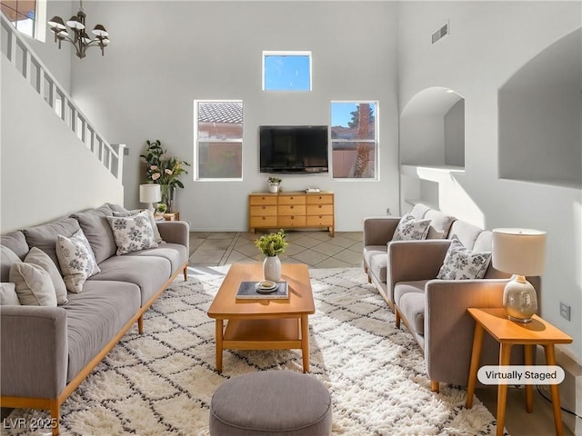 living room with a towering ceiling, light tile patterned floors, and an inviting chandelier