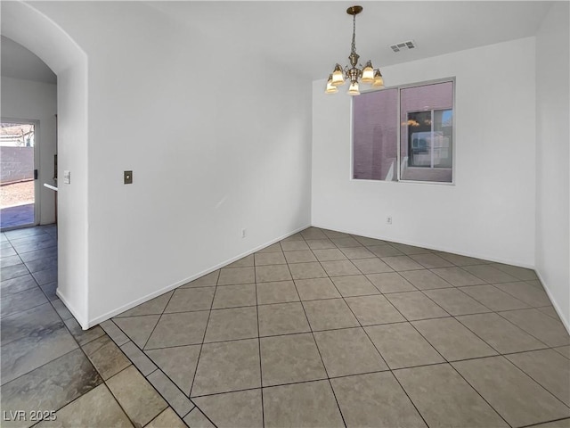 spare room featuring tile patterned flooring and a chandelier