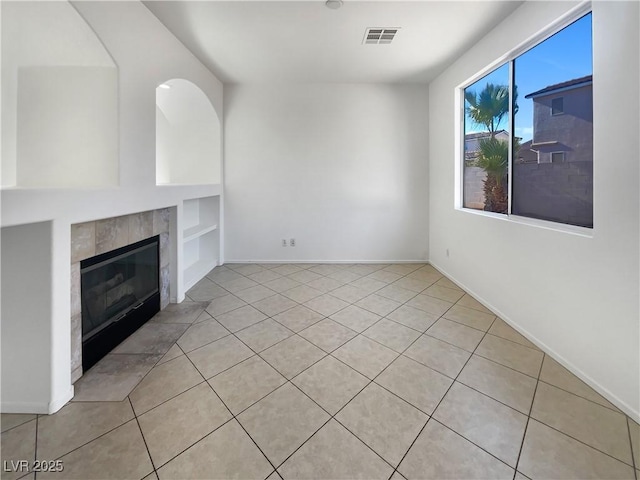 unfurnished living room featuring a fireplace, built in features, and light tile patterned flooring