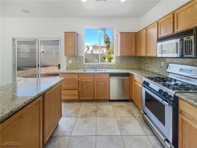 kitchen featuring light stone countertops, backsplash, stainless steel appliances, sink, and light tile patterned floors