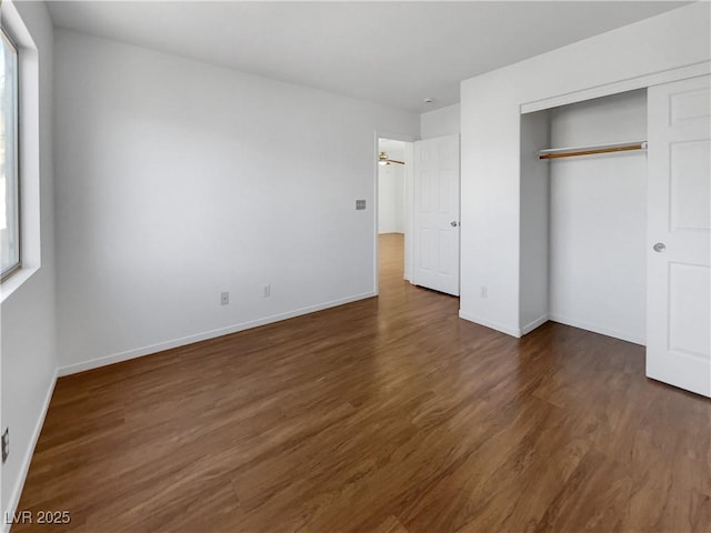 unfurnished bedroom featuring multiple windows, a closet, and dark wood-type flooring