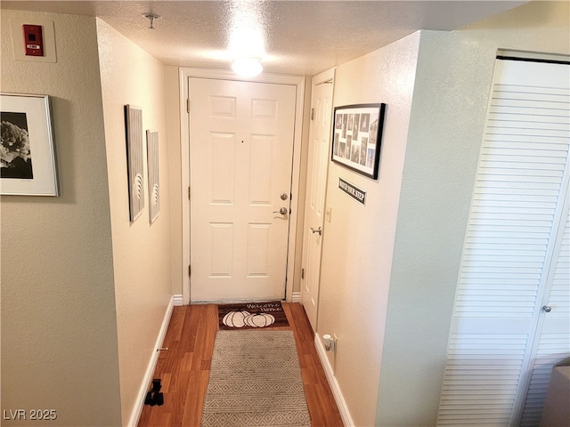 doorway to outside with a textured ceiling and dark hardwood / wood-style flooring