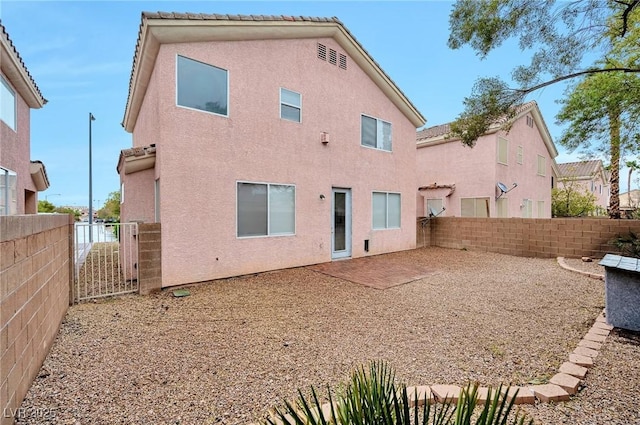 rear view of property featuring a patio, a tiled roof, a fenced backyard, and stucco siding