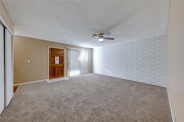 interior space featuring light carpet, a textured ceiling, ceiling fan, and brick wall