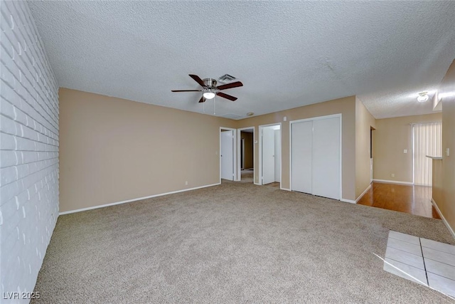 unfurnished bedroom featuring carpet, a textured ceiling, and ceiling fan