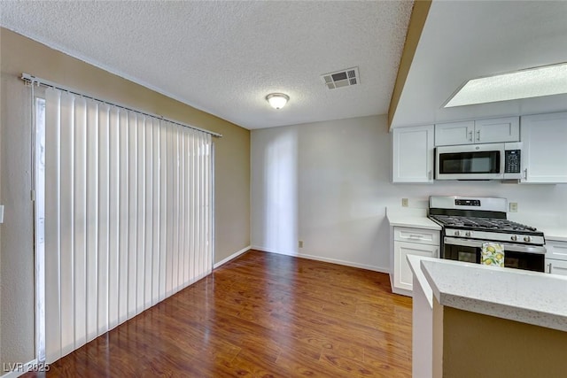 kitchen with white cabinetry, stainless steel appliances, a textured ceiling, and light hardwood / wood-style floors