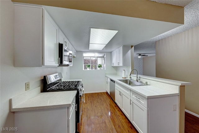 kitchen featuring kitchen peninsula, white cabinetry, sink, and appliances with stainless steel finishes