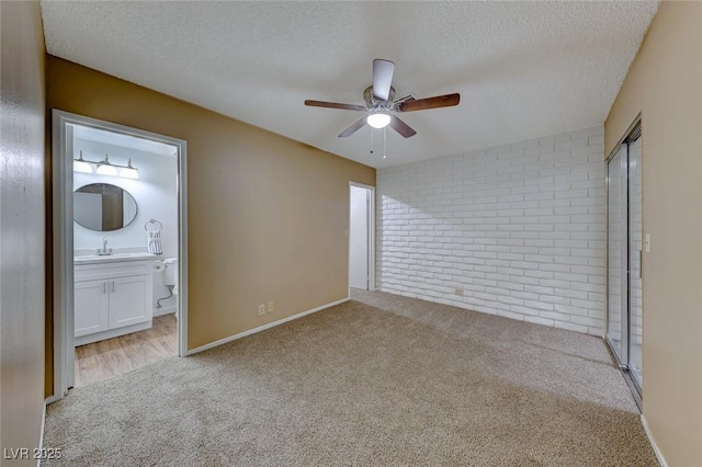 unfurnished bedroom with ceiling fan, a closet, light carpet, and ensuite bath