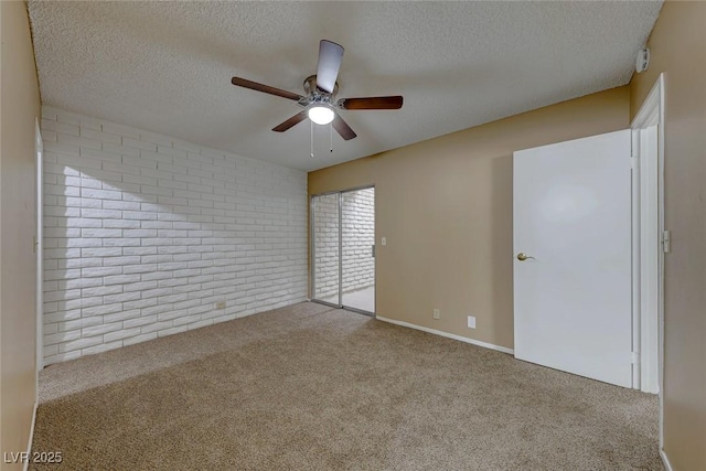 empty room with ceiling fan, light colored carpet, a textured ceiling, and brick wall