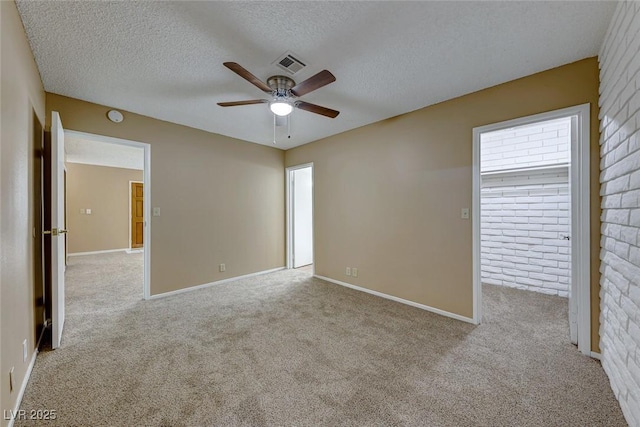 empty room with ceiling fan, light colored carpet, and a textured ceiling