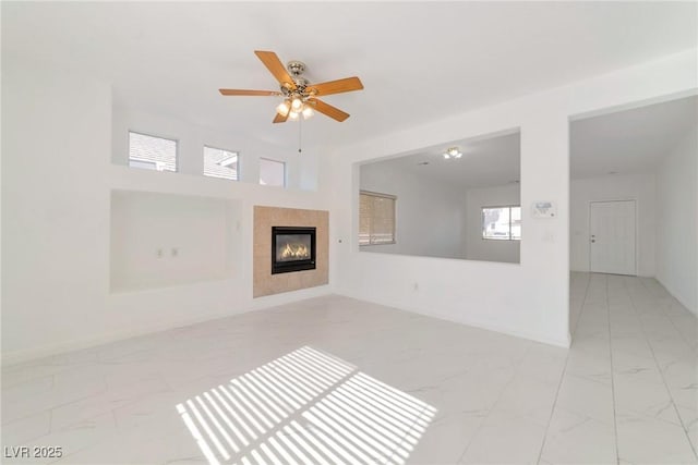 unfurnished living room featuring ceiling fan and a tile fireplace