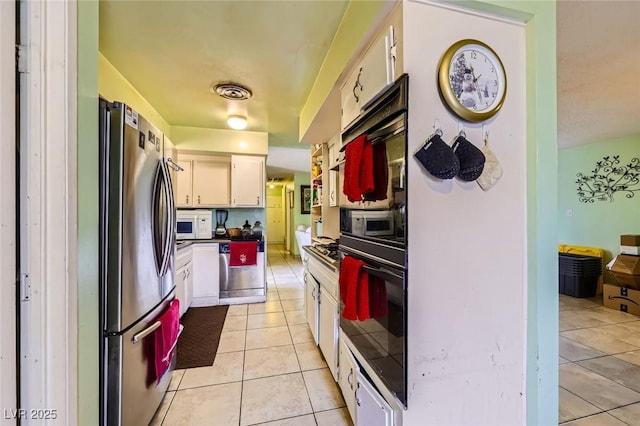 kitchen featuring dark countertops, visible vents, appliances with stainless steel finishes, light tile patterned flooring, and white cabinets