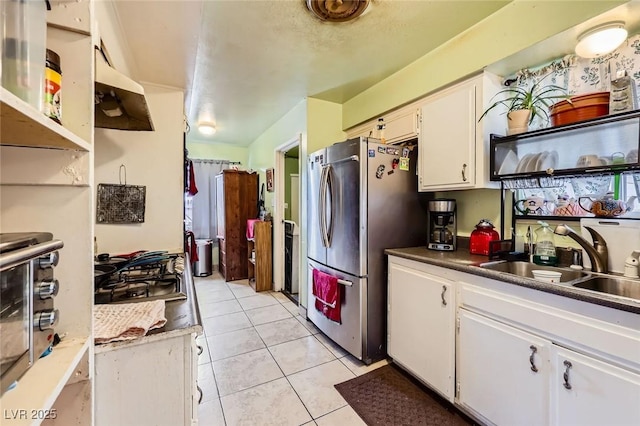 kitchen featuring light tile patterned floors, appliances with stainless steel finishes, white cabinetry, and a sink