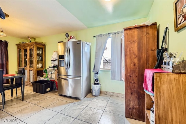 kitchen featuring light tile patterned floors, baseboards, and stainless steel refrigerator with ice dispenser