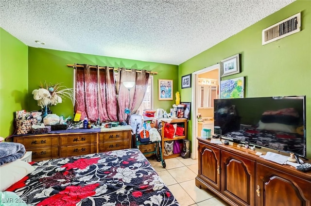 bedroom featuring light tile patterned floors, visible vents, and a textured ceiling