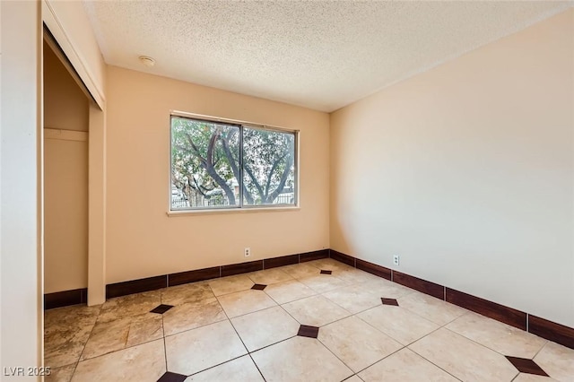 unfurnished bedroom featuring light tile patterned flooring, baseboards, a closet, and a textured ceiling