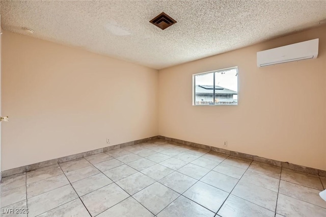 unfurnished room featuring a wall unit AC, light tile patterned floors, visible vents, baseboards, and a textured ceiling