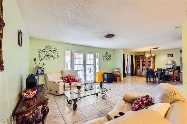 living area with light tile patterned floors, french doors, a chandelier, and a textured ceiling