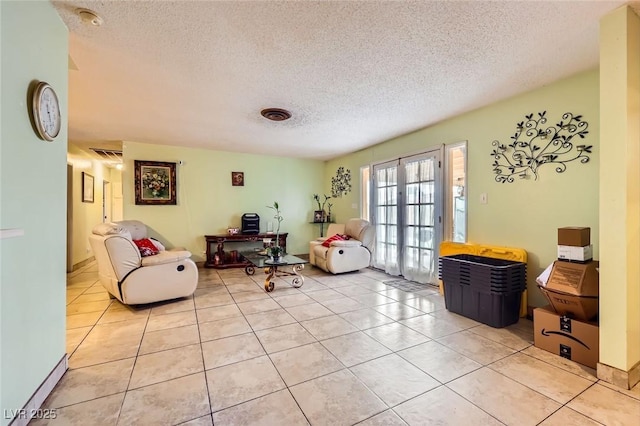 living area featuring light tile patterned flooring, french doors, and a textured ceiling