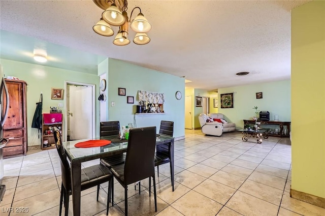 dining area with an inviting chandelier, light tile patterned floors, and a textured ceiling