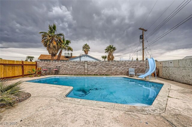 view of pool featuring a patio, a fenced backyard, a fenced in pool, and a water slide