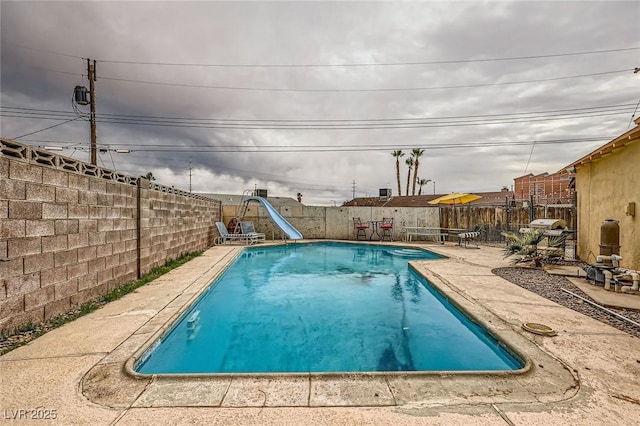 view of swimming pool featuring a fenced in pool, a water slide, a fenced backyard, and a patio area