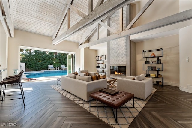 living room featuring beam ceiling, a large fireplace, parquet floors, and a high ceiling