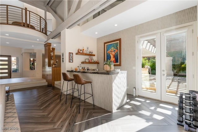 bar featuring a towering ceiling, french doors, and dark parquet floors