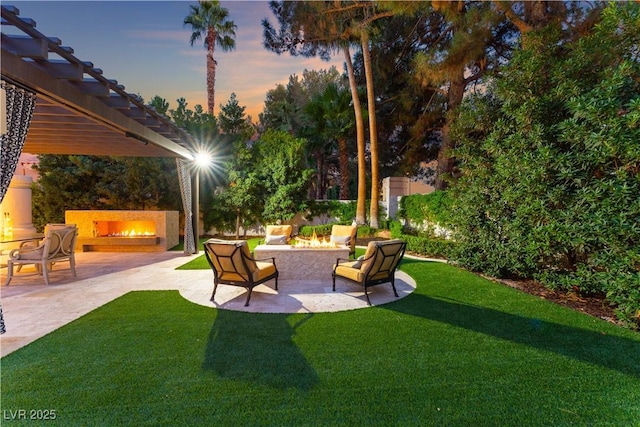 yard at dusk with a patio area and exterior fireplace