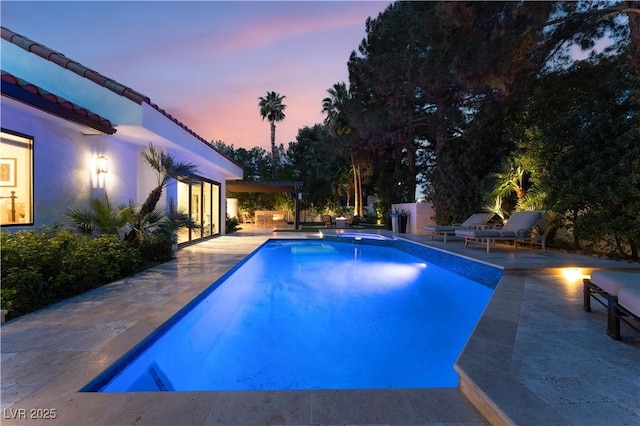 pool at dusk featuring a patio