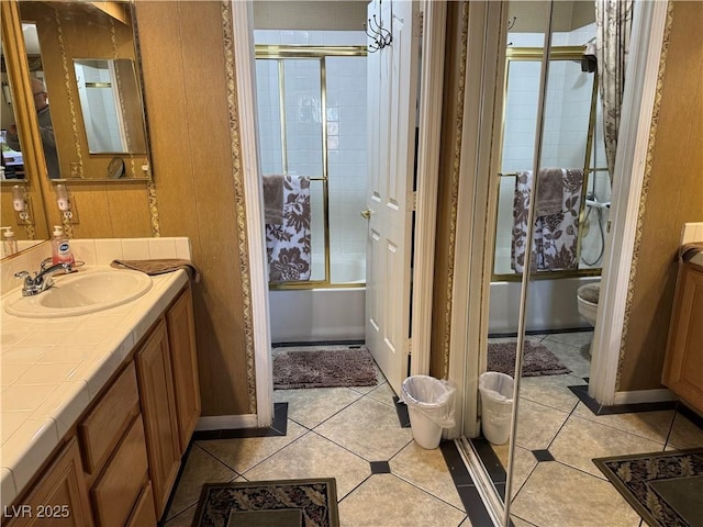 full bathroom featuring shower / bath combination with glass door, tile patterned flooring, vanity, and toilet