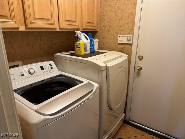 clothes washing area with tile patterned flooring, cabinets, and separate washer and dryer