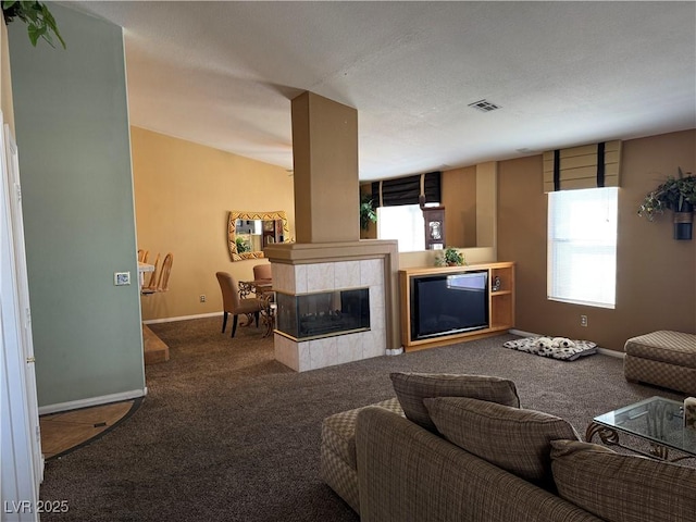 living room featuring carpet flooring, a wealth of natural light, and a tiled fireplace