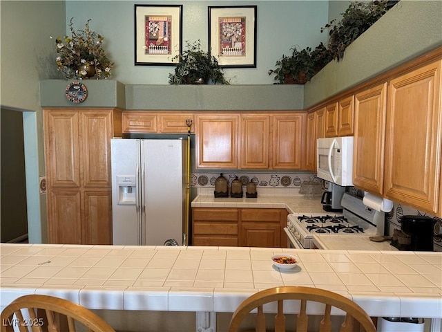 kitchen with tile counters, white appliances, and kitchen peninsula