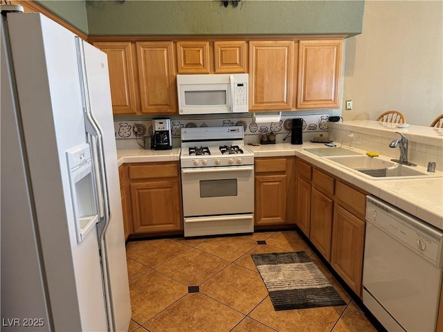 kitchen featuring light tile patterned floors, white appliances, tile countertops, and sink