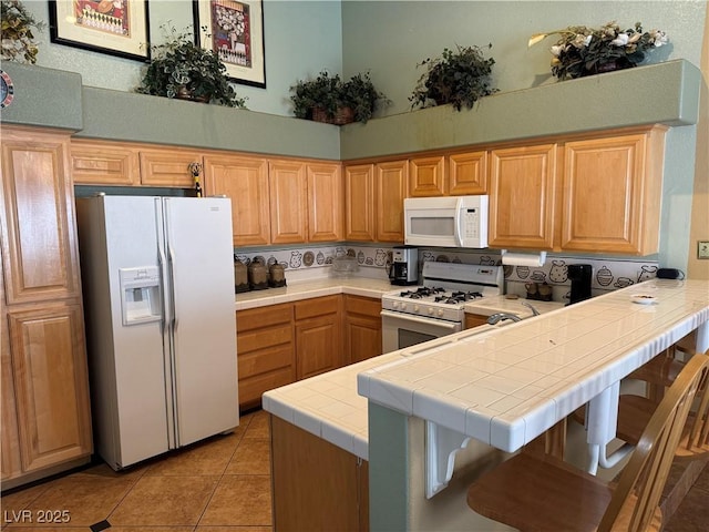 kitchen with tile countertops, white appliances, a towering ceiling, light tile patterned flooring, and kitchen peninsula