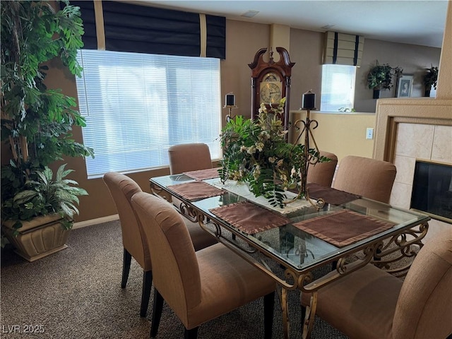 carpeted dining area with a tile fireplace