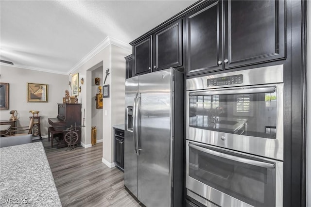 kitchen with appliances with stainless steel finishes, light wood-type flooring, and ornamental molding