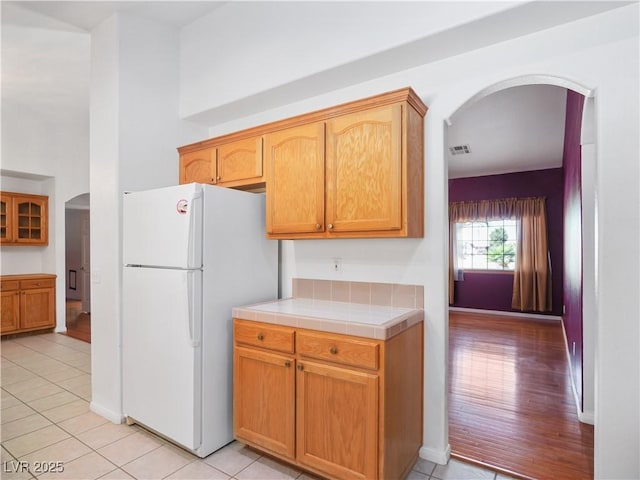 kitchen with tile counters, white fridge, and light tile patterned flooring