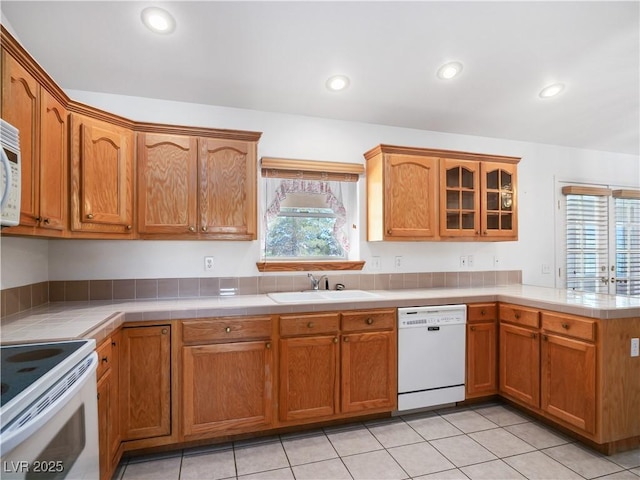 kitchen featuring tile countertops, white appliances, sink, and light tile patterned floors