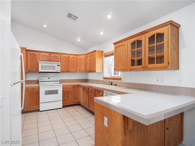 kitchen featuring kitchen peninsula, tile countertops, lofted ceiling, white appliances, and light tile patterned flooring