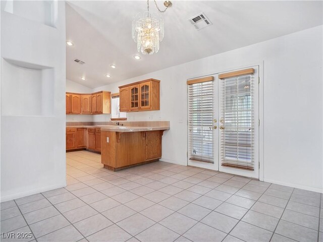 kitchen featuring a kitchen breakfast bar, kitchen peninsula, a chandelier, vaulted ceiling, and light tile patterned floors