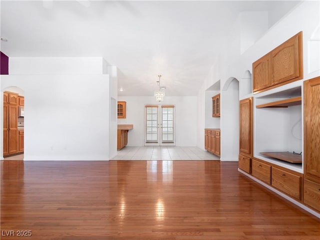 unfurnished living room featuring light hardwood / wood-style floors, an inviting chandelier, and french doors